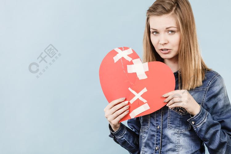 悲伤的年轻十几岁的女子与心脏破纸做的消极的情绪悲伤感情问题的概念