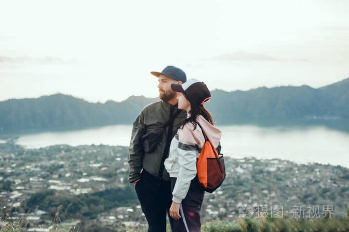 情侣旅行者男女坐在悬崖上放松的山和云鸟瞰爱情和旅行快乐的情感生活